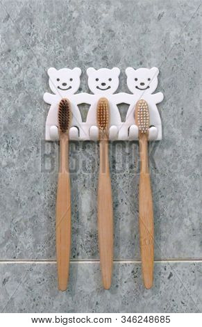 A Family Set Of Three Bamboo Toothbrushes Hang On The Bathrooms Wall In Toothbrush Holder. Ecologica