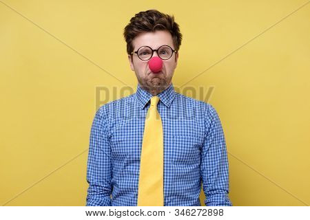 Caucasian Young Man In Red Clown Nose Being Irritated And Sad.