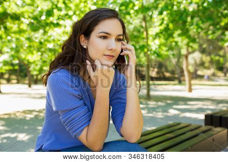 Calm Young Woman Holding Hand On Chin While Talking On Phone. Tranquil Lady Listening Interlocutor T