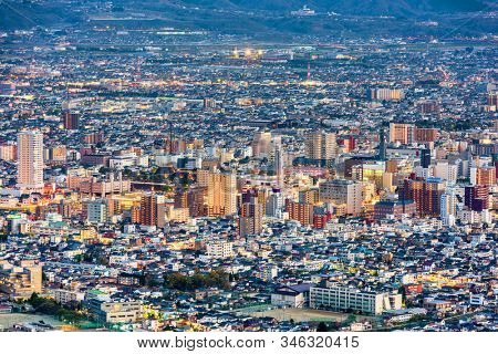 Kofu, Yamanashi, Japan downtown city skyline from the mountains at dusk.