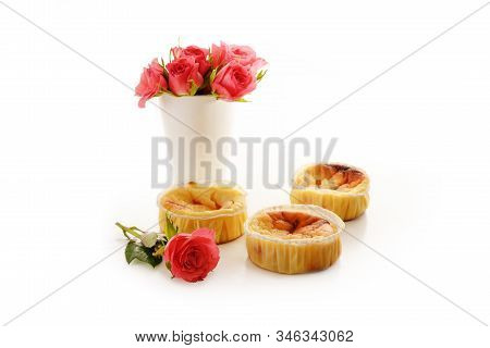Homemade Small Curd Cakes Or Muffins And A Vase With Pink Roses Isolated With Shadows On A White Bac