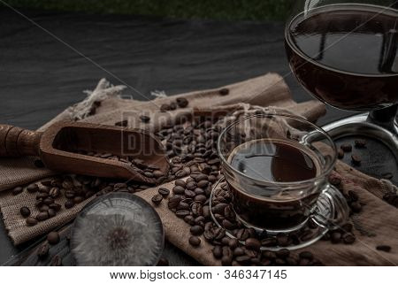 Coffee Style, Cup Of Coffee And Coffee Beans Roating With Old Wooden Scoop And Coffee Beans Around O