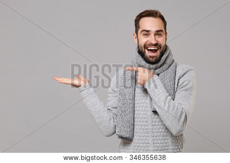 Funny Young Man In Gray Sweater, Scarf Posing Isolated On Grey Wall Background, Studio Portrait. Hea