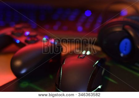 Modern Gamepad And Gaming Mouse Lies With Keyboard And Headphones On Table In Dark Playroom Scene. V