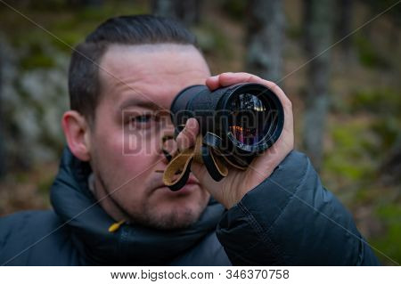 Traveler With Monocle Sitting On Big Stone In Deep Forest And Looks Into The Distance, Selective Foc