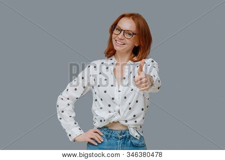 Pleasant Looking Confident Woman With Ginger Hair, Shows Thumb Up, Says Very Good And Encourages Fri