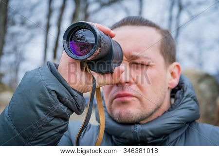 Traveler With Monocle Sitting On Big Stone In Deep Forest And Looks Into The Distance, Selective Foc