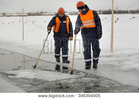 Workers Rafting Ice Blocks Along A Channel Cut Out By A Frozen Lake