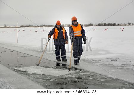 Workers Rafting Ice Blocks Along A Channel Cut Out By A Frozen Lake