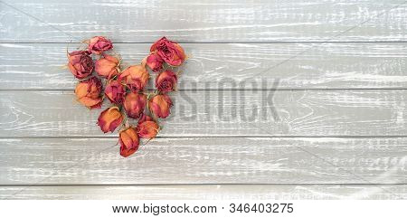Dried Red-yellow Flowers And Buds Of Roses In Shape Of Tender Heart On Background Of Wooden Boards R