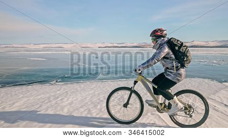 Woman Is Riding Bicycle On The Ice. Tires On Bike Are Covered Wi