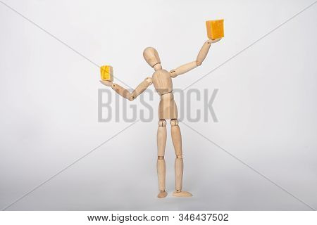 Wooden Manikin Figure Standing Holding Up Blocks Of Cheddar Cheese On Solid Background