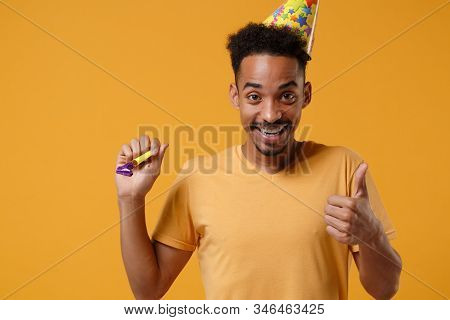 Smiling Young African American Guy In Casual T-shirt, Birthday Hat Posing Isolated On Yellow Orange 