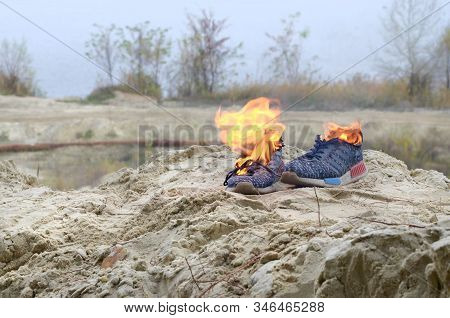 Burning Sports Sneakers Or Gym Shoes On Fire Stand On Sandy Beach Coast. Athlete Burned Out. Physica