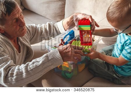Elderly Grandpa Or Grandfather Plays With His Little Grandson