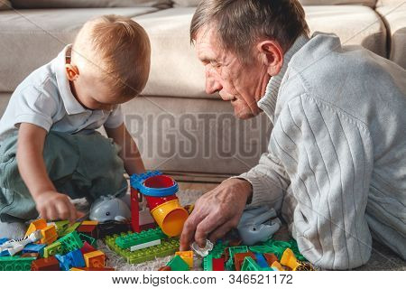 Elderly Grandpa Or Grandfather Plays With His Little Grandson
