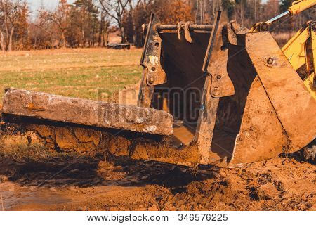The Yellow Excavator Transports Concrete Slabs In The Countryside.