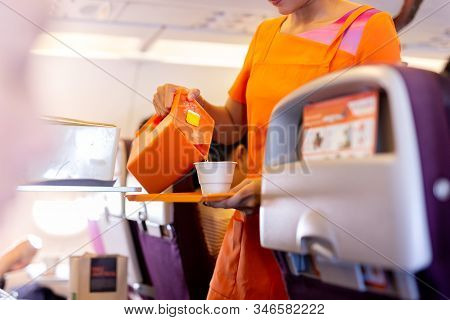 Flight Attendant Serving Hot Drinks To Passengers On Board.