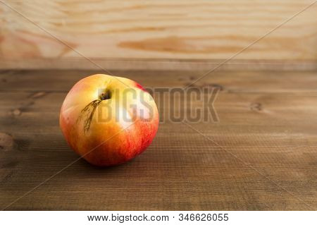 Juicy, Ugly, Apple With Defects On The Skin On The Wooden Brown Background. Strange, Imperfect Fruit