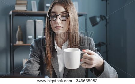 Young Woman In Formal Clothing Having Coffee Or Tea While Working Staying At Working Place In Office