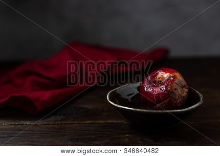 Art Concept Of The Problem Of Food Consumption. Red Rotten Apple On A Plate With Tehstil On A Wooden
