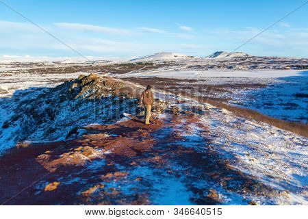 Amazing Winter Landscape Near Kerid Lake. The Guy Walks Near The Crater Of The Volcano Kerid In Wint