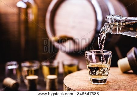 Glass Of Golden Rum, With Bottle. Bottle Pouring Alcohol Into A Small Glass. Brazilian Export Type D