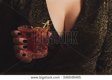 Girl In Evening Dress With Big Breast Holds An Alcohol Cocktail In A Hand. Hot Woman At The Party. T