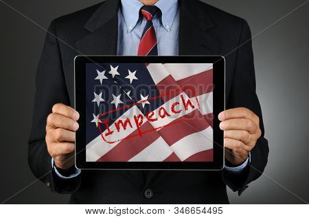 Politician Holding Tablet with American Flag and the Word Impeach. Man is  unrecognizable.