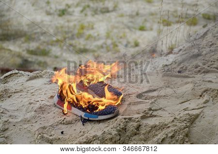 Burning Sports Sneakers Or Gym Shoes On Fire Stand On Sandy Beach Coast. Athlete Burned Out. Physica