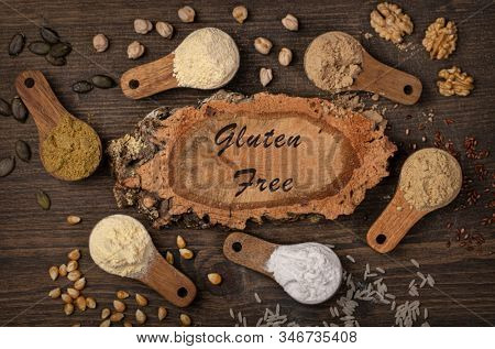 Gluten free flours in wooden spoons on a brown background