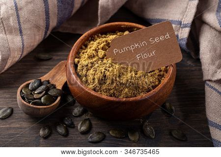 Pumpkin seed flour  in a wooden bowl  isolated on a white background