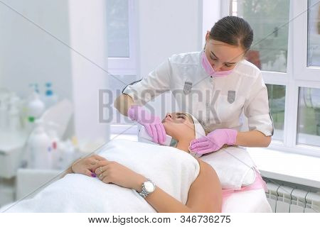 Cosmetologist Making Ultrasonic Face Cleaning Procedure For Young Woman Client In Clinic. Beutician 
