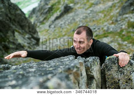 Young Man Makes Hard Climbing A Steep Rock Without A Rope. Rock-climb Extreme Sport. Tourist Man Hik