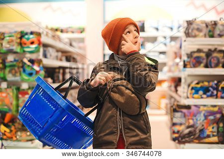 Boy Choosing Toy In Big Assortement In Supermarket. It Is Difficult Choice To Buy A Interesting Toy.