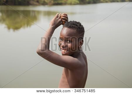 Bissau, Guinea-Bissau - January 11, 2020: portrait on an African Kid smiling to camera near the water in rural Guinea-Bissau
