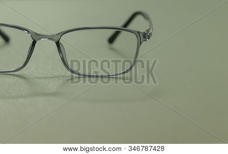 clear plastic glasses, eyes closed, shot close-up, on a blurred green background. Concept: beautiful