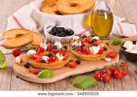 Friselle With Tomatoes And Mozzarella Cheese On Cutting Board.
