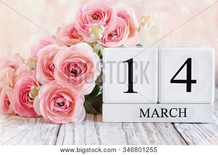 White Wood Calendar Blocks With The Date March 14th And Pink Ranunculus Flowers Over A Wooden Table.