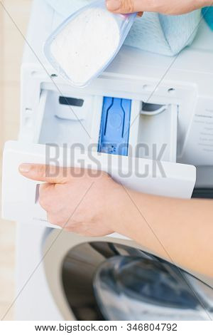 Washing Powder Detergent And Measuring Cup Pouring Into Machine. Household Duties, Clothes Laundry O