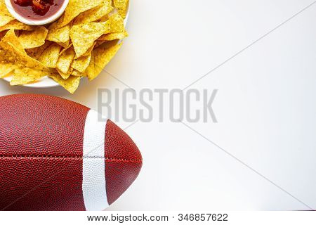 An American Football With Organic Nacho Chips And Mild Salsa On The Side On A White Background
