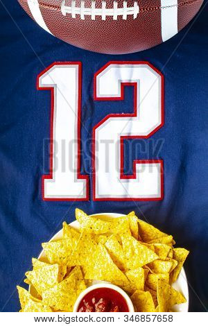 An American Football With Organic Nacho Chips And Mild Salsa On A White Blue Football Jersey With Th