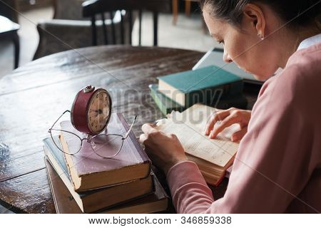 Too Little Time. An Alarm Clock Stands On A Stack Of Books, Next To Glasses, On A Table In An Old Li