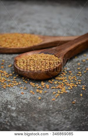 Fenugreek Seeds In Wooden Spoon On Textured Background