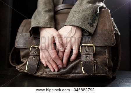 Teacher Holds An Old, Brown, Classic, Leather Briefcase With Metal Buckles, Which Stands On A Black 