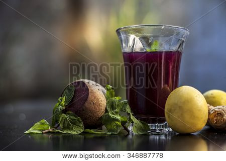 Beetroot Juice With Some Mint Leaves Lemon Juice And Ginger In It On Black Glossy Surface In A Glass