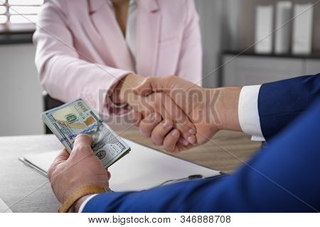 Man Shaking Hands With Woman And Offering Bribe At Table, Closeup