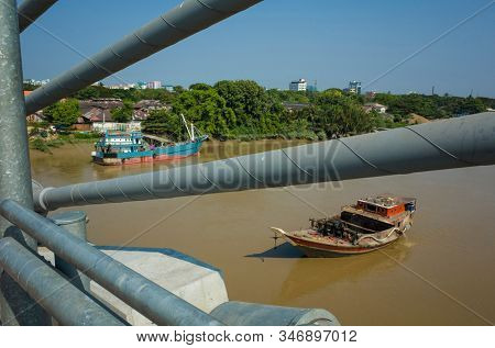 Old wooden ship on brown water of Pazundaung Greek view from Thaketa Bridge. Yangon, Myanmar
