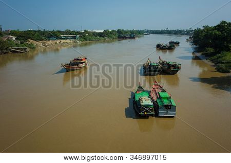 Boats on brown water of Pazundaung Greek. Yangon, Myanmar