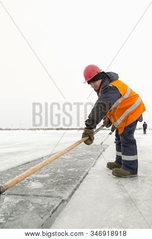 Worker Rafts Ice Blocks Along A Canal Carved In A Frozen Lake